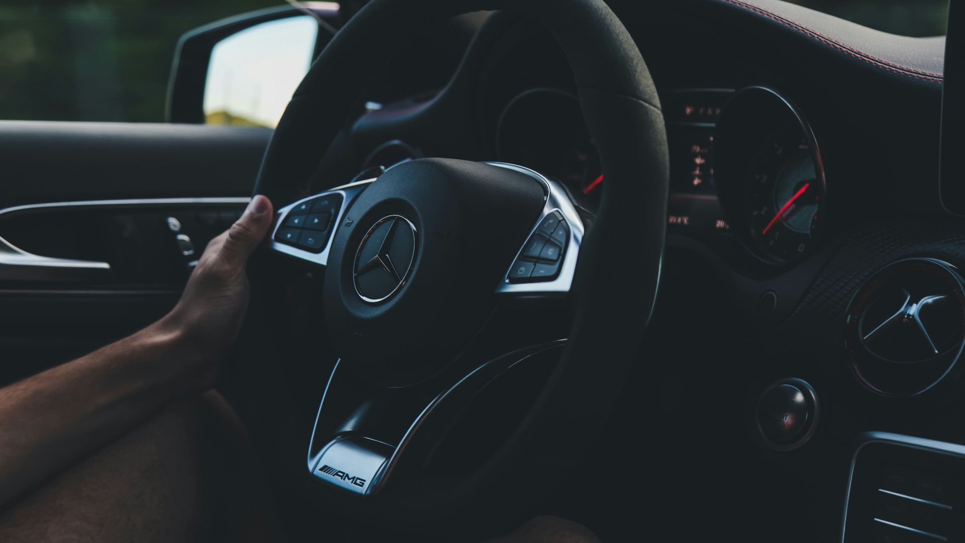 person holding on black steering wheel inside car