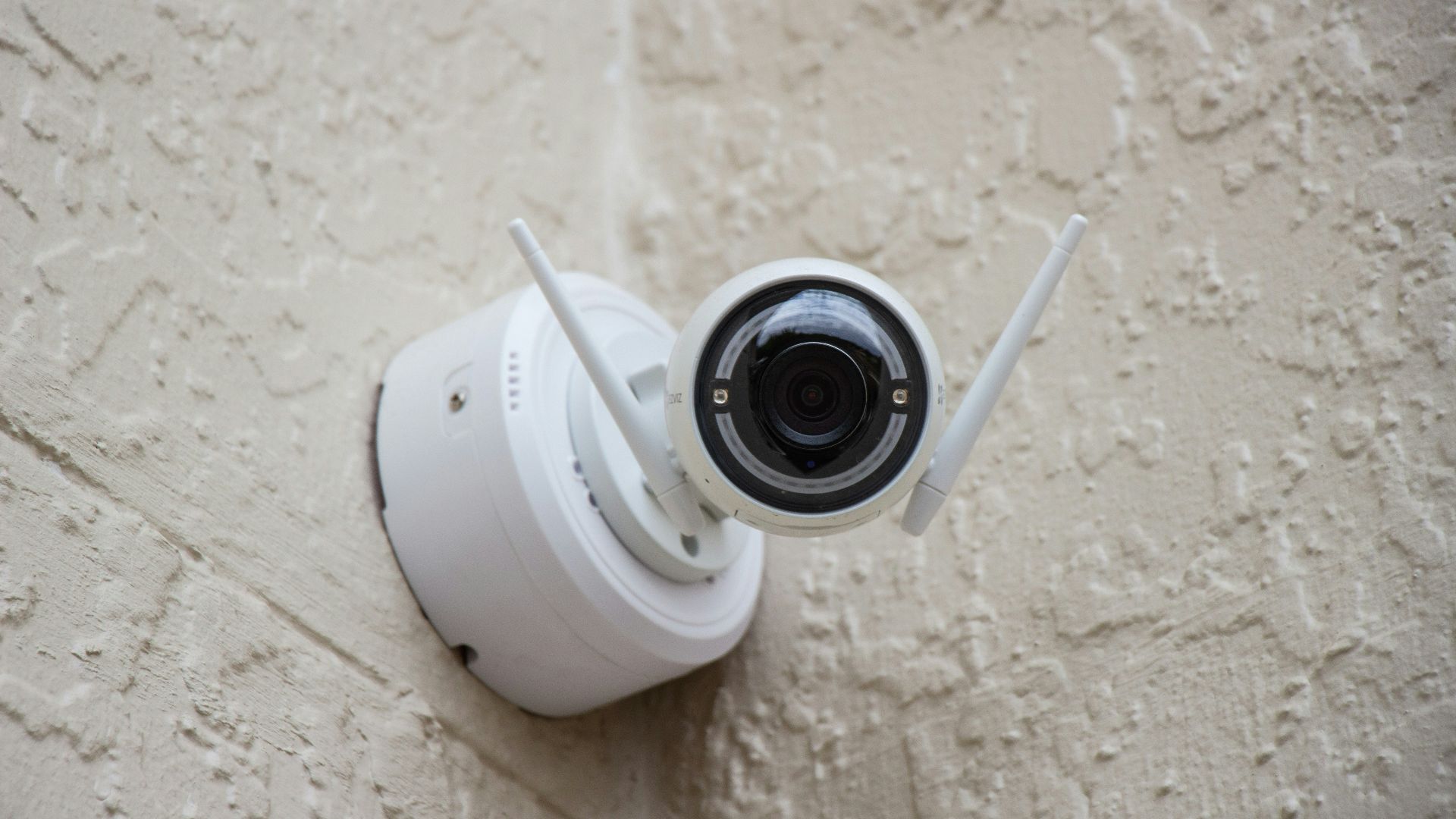 white surveillance camera hanging on wall