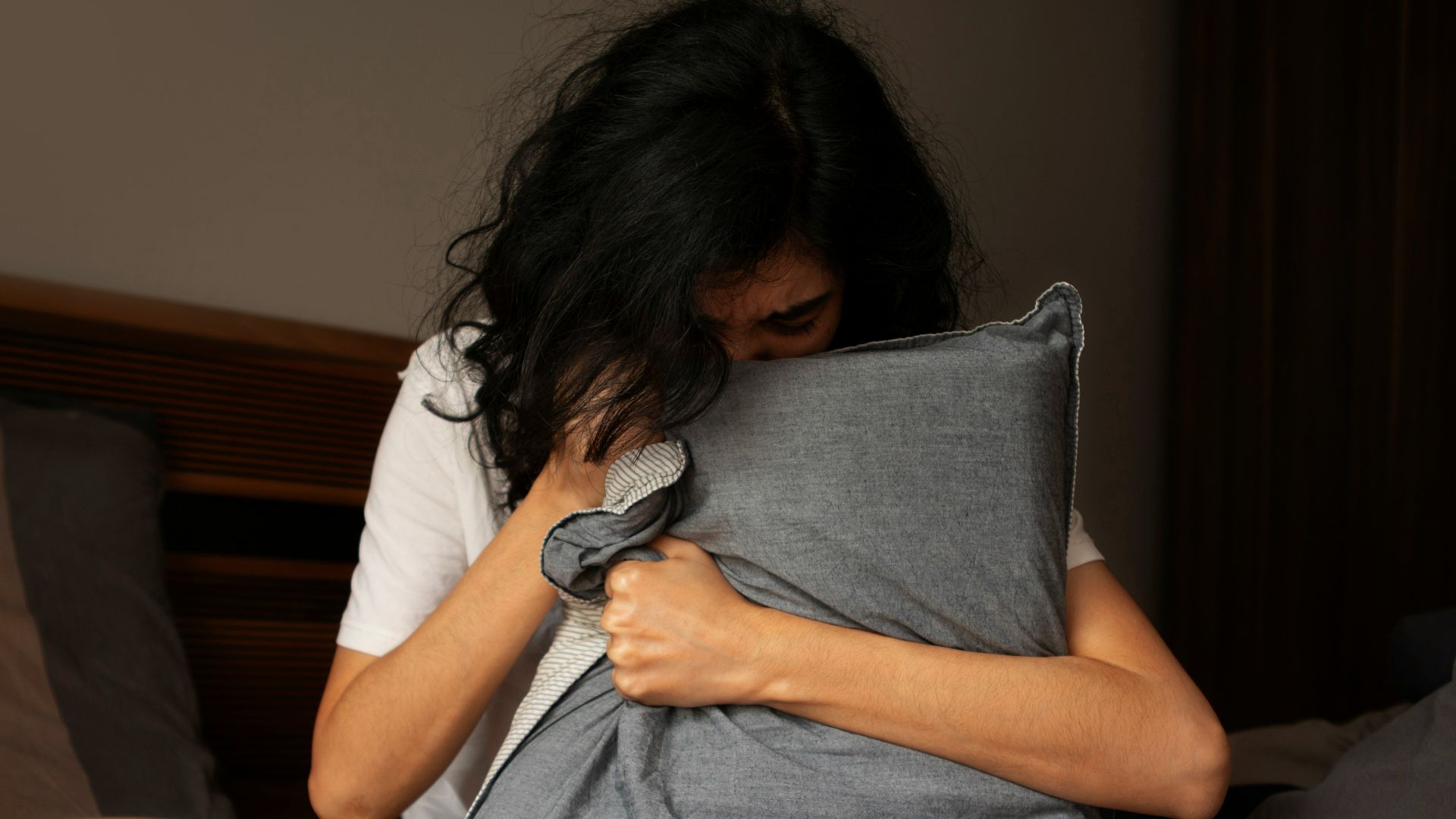 A woman sitting on a bed holding a pillow