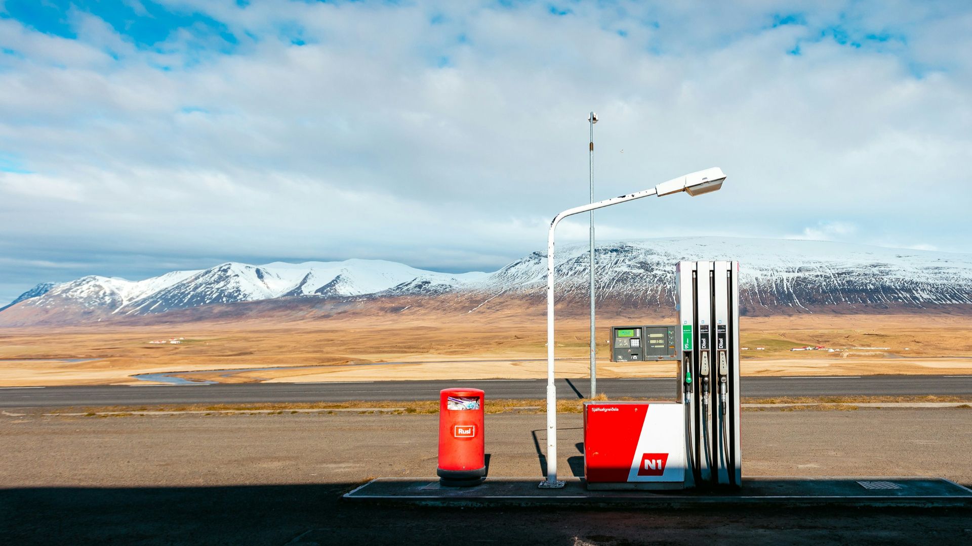 empty gas station near empty road facing snow capped mountain at daytime