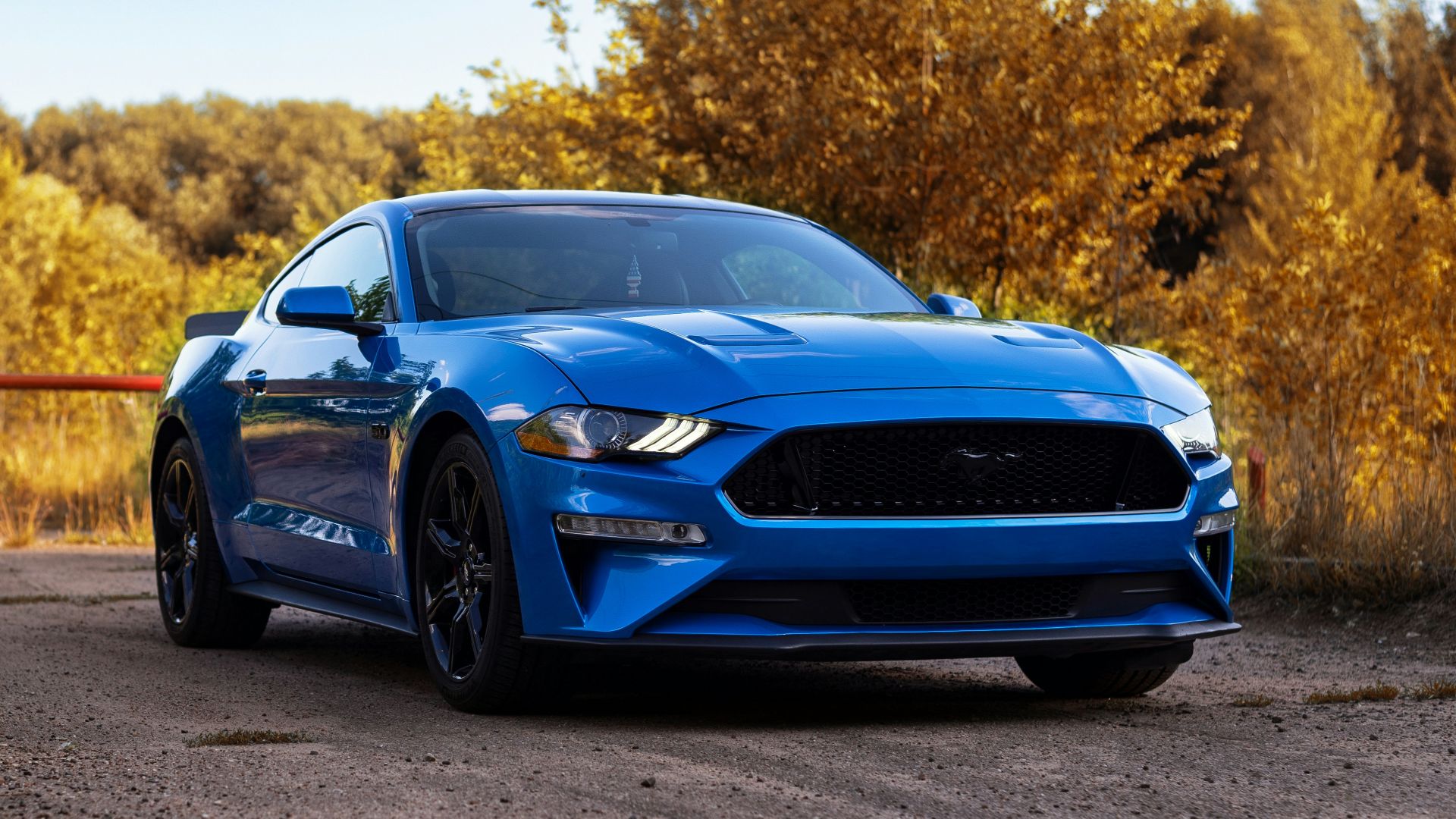 a blue mustang parked on a dirt road