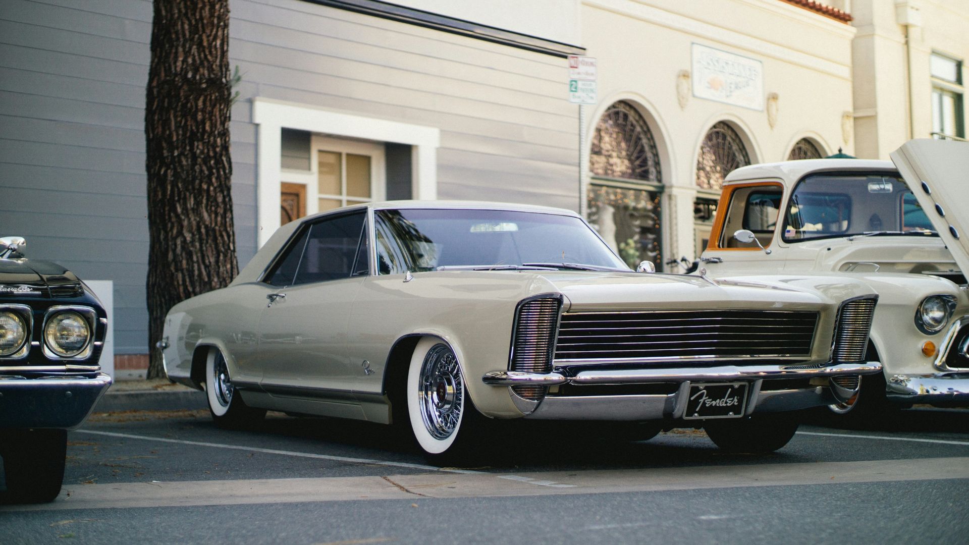 white coupe parked near tree and building