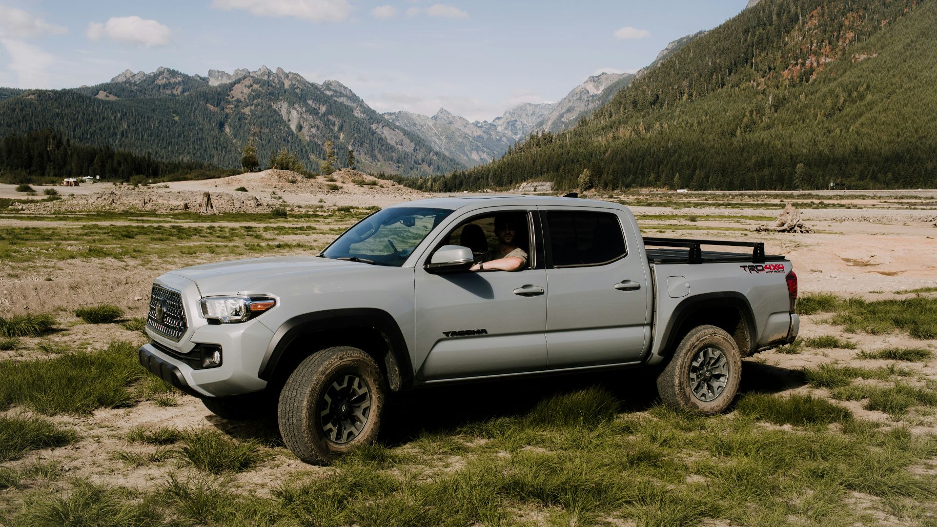 a truck parked in a field with mountains in the background