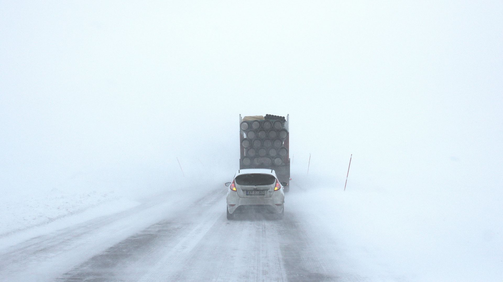 white car behind a truck on snowy road