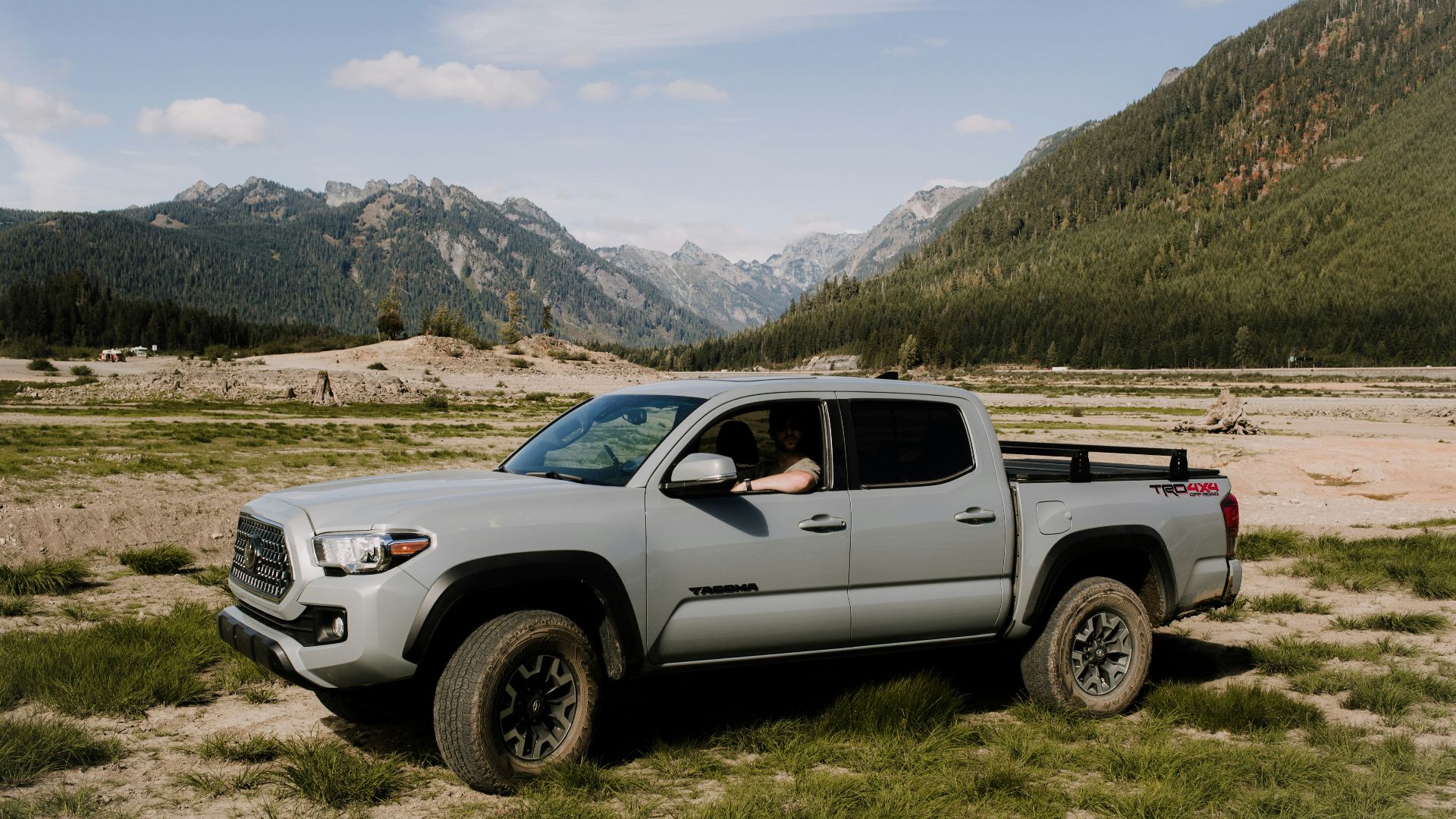 a truck parked in a field with mountains in the background