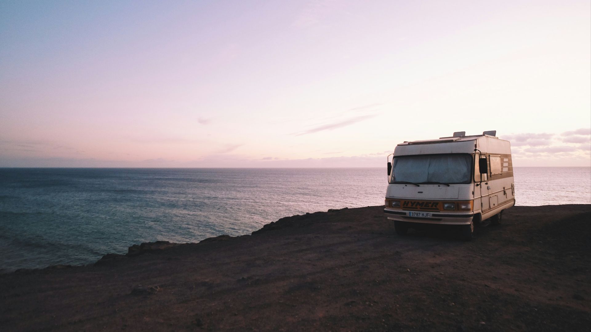 RV parked beside the edge of island during sunset