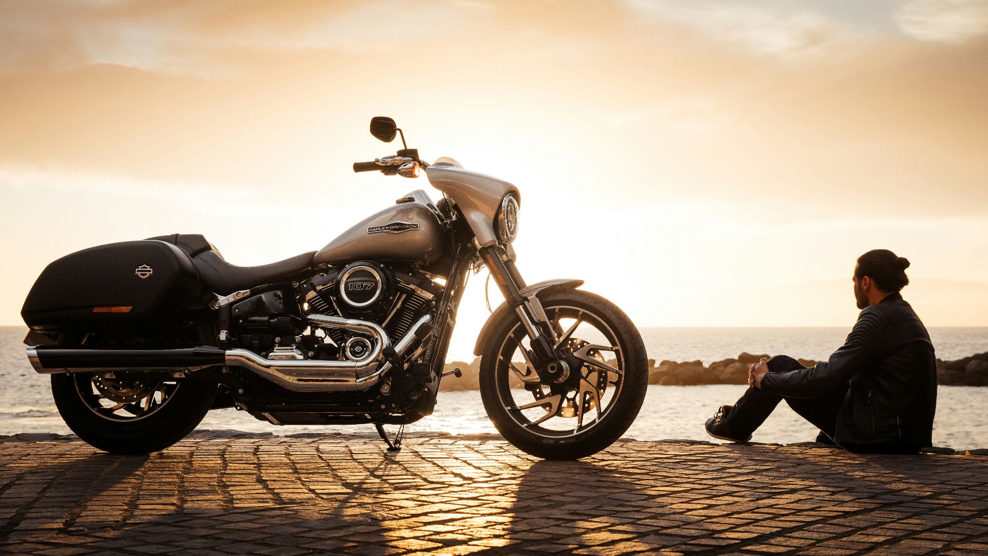 man sitting on ground beside parked silver cruiser motorcycle