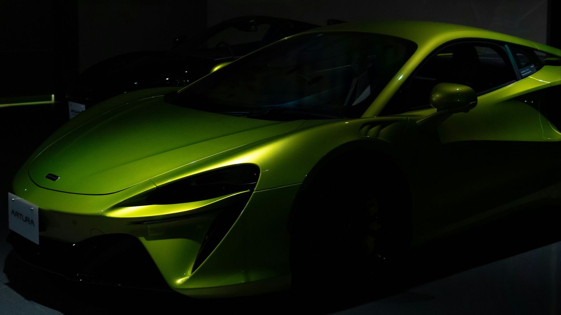 a green sports car parked in a dark room