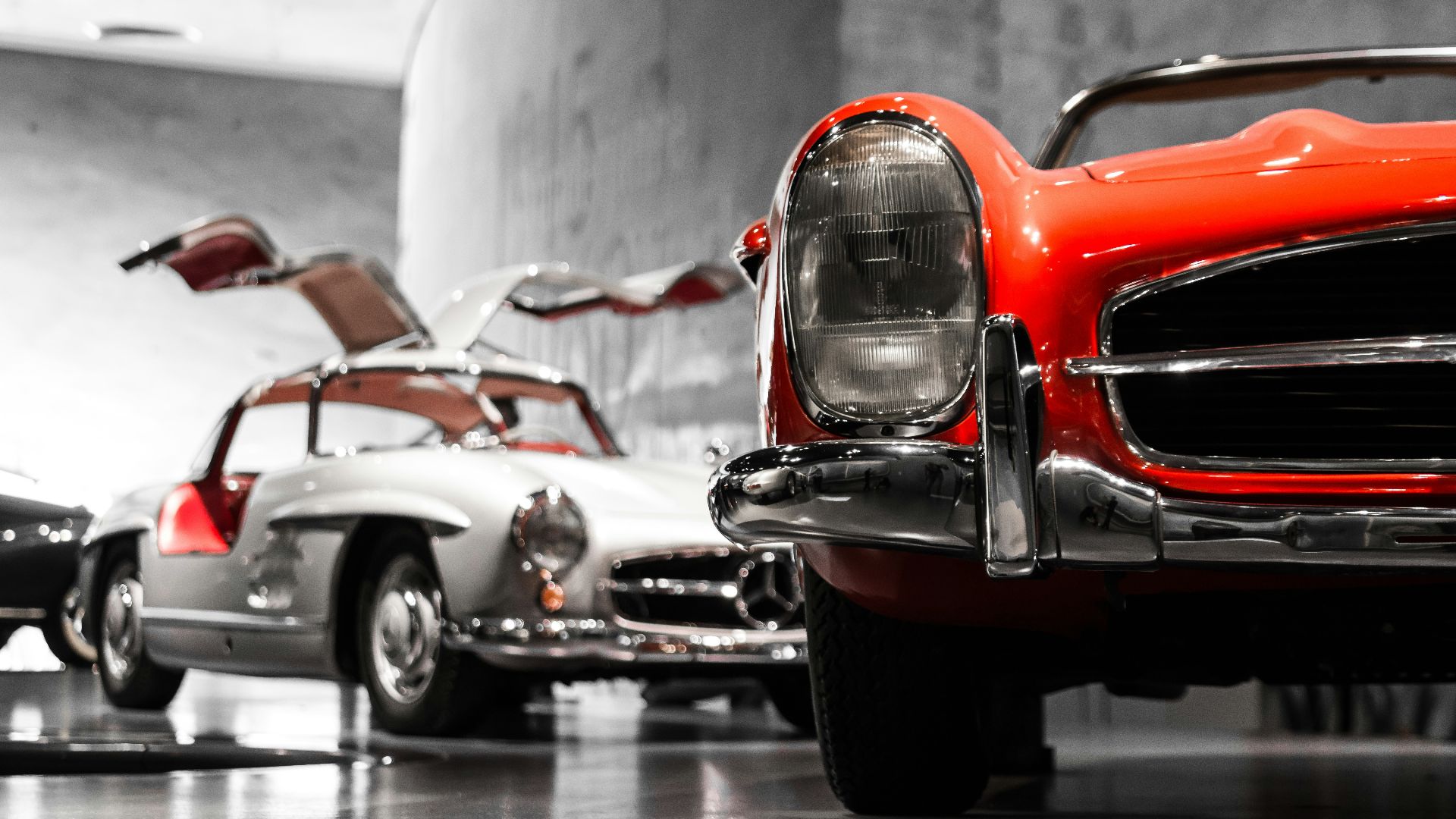 two vintage cars beside gray concrete wall