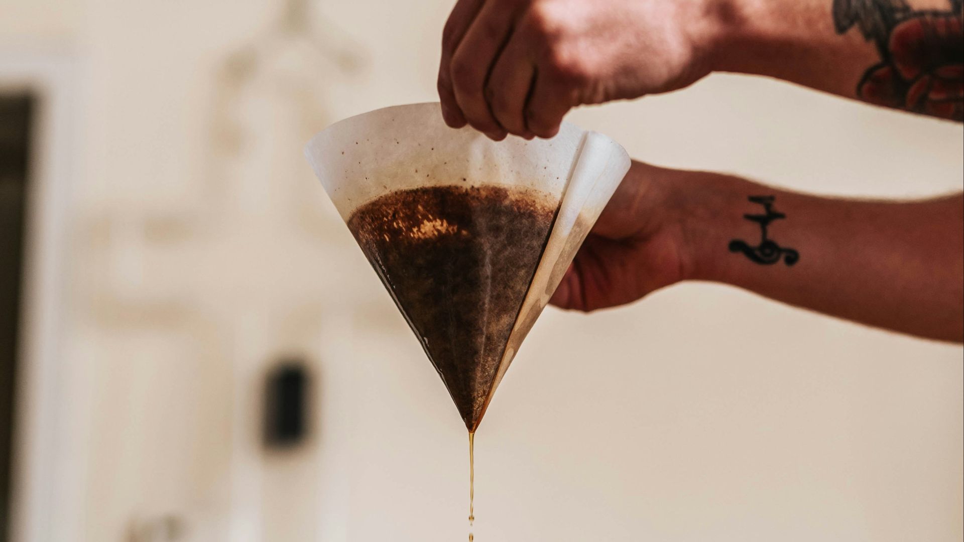person filtering coffee in funnel