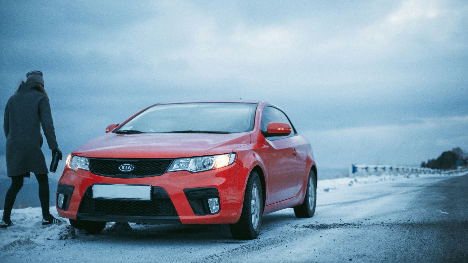 person standing beside Kia coupe