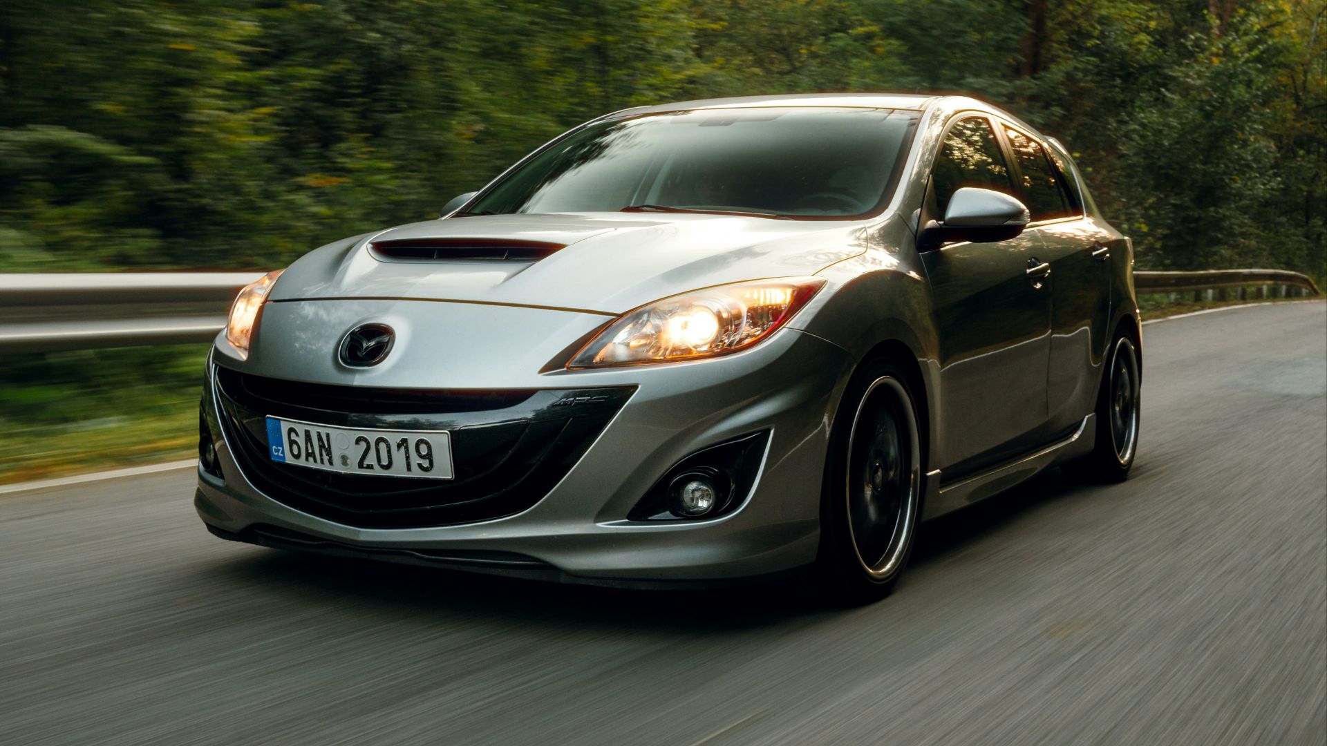 A car driving down a road with trees in the background