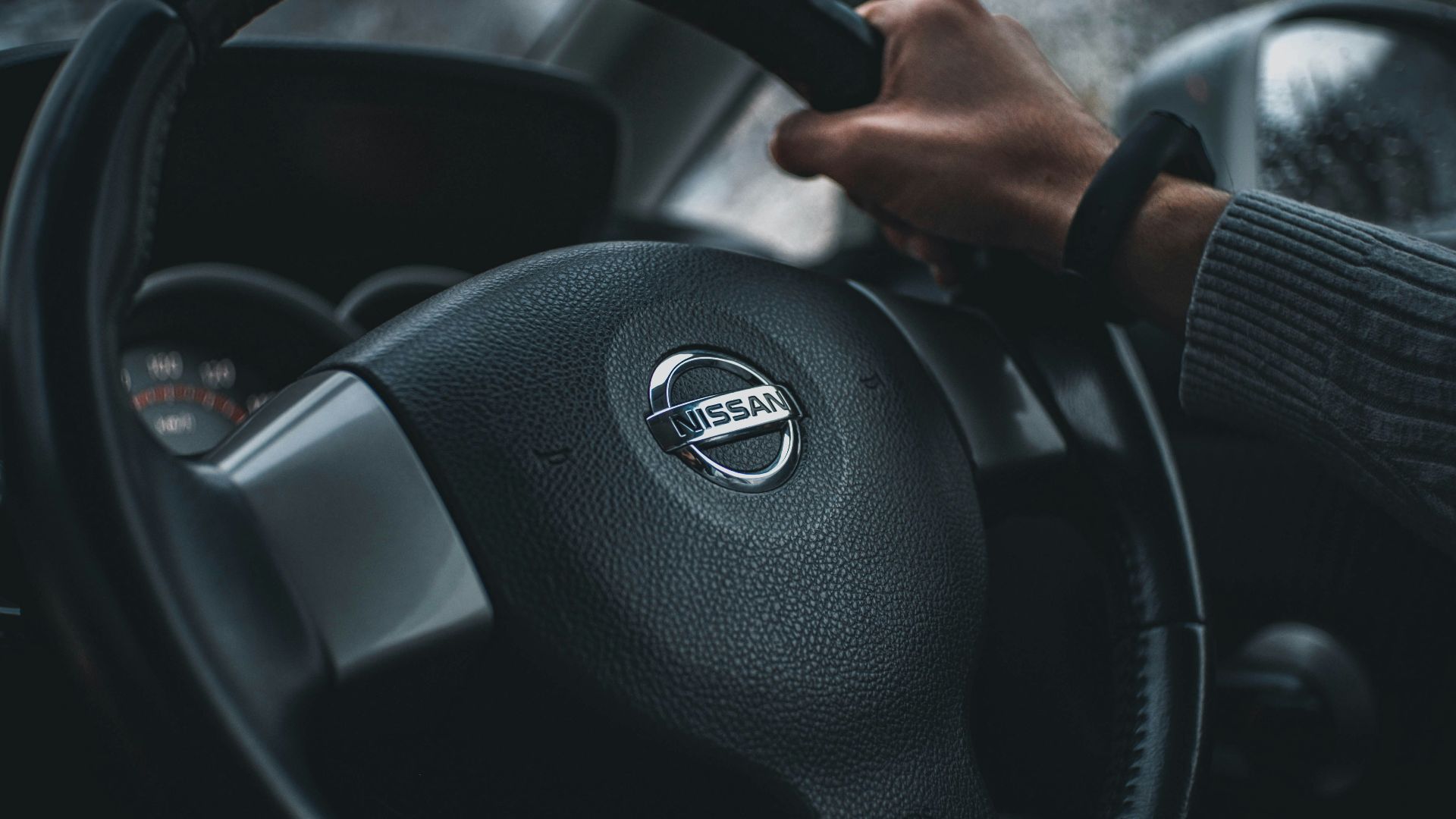 person holding black nissan steering wheel