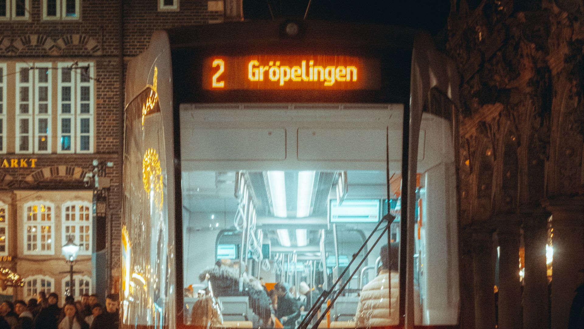 A white bus driving down a street next to tall buildings
