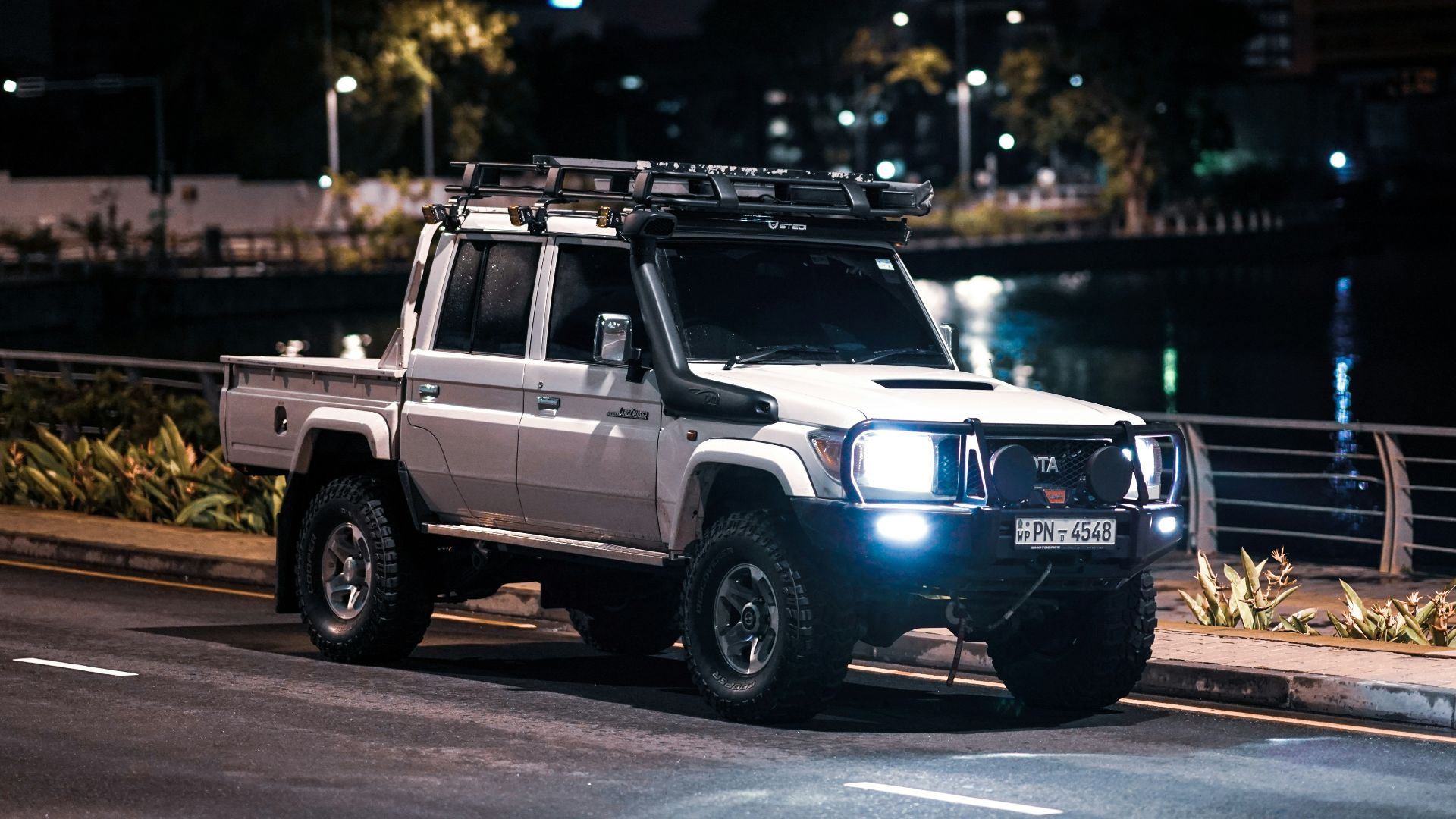 a white truck driving down a street at night