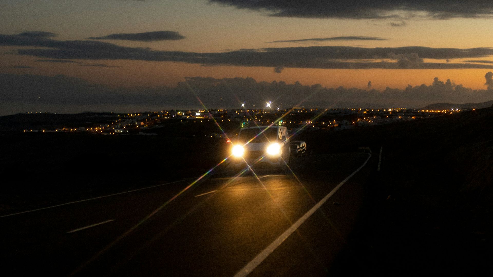 a road with cars on it and a sunset in the background