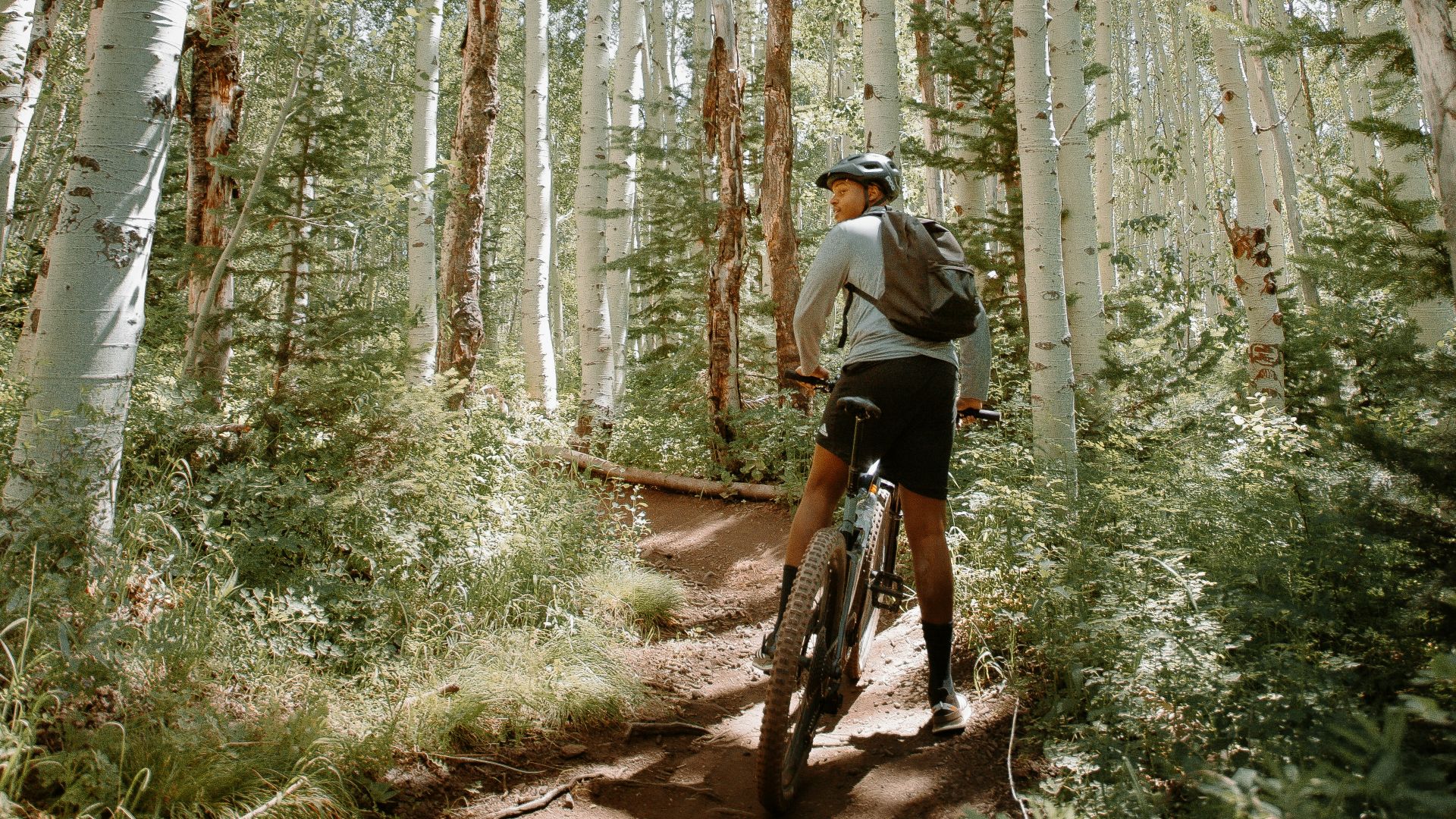 man in black shirt and black shorts riding bicycle in forest during daytime