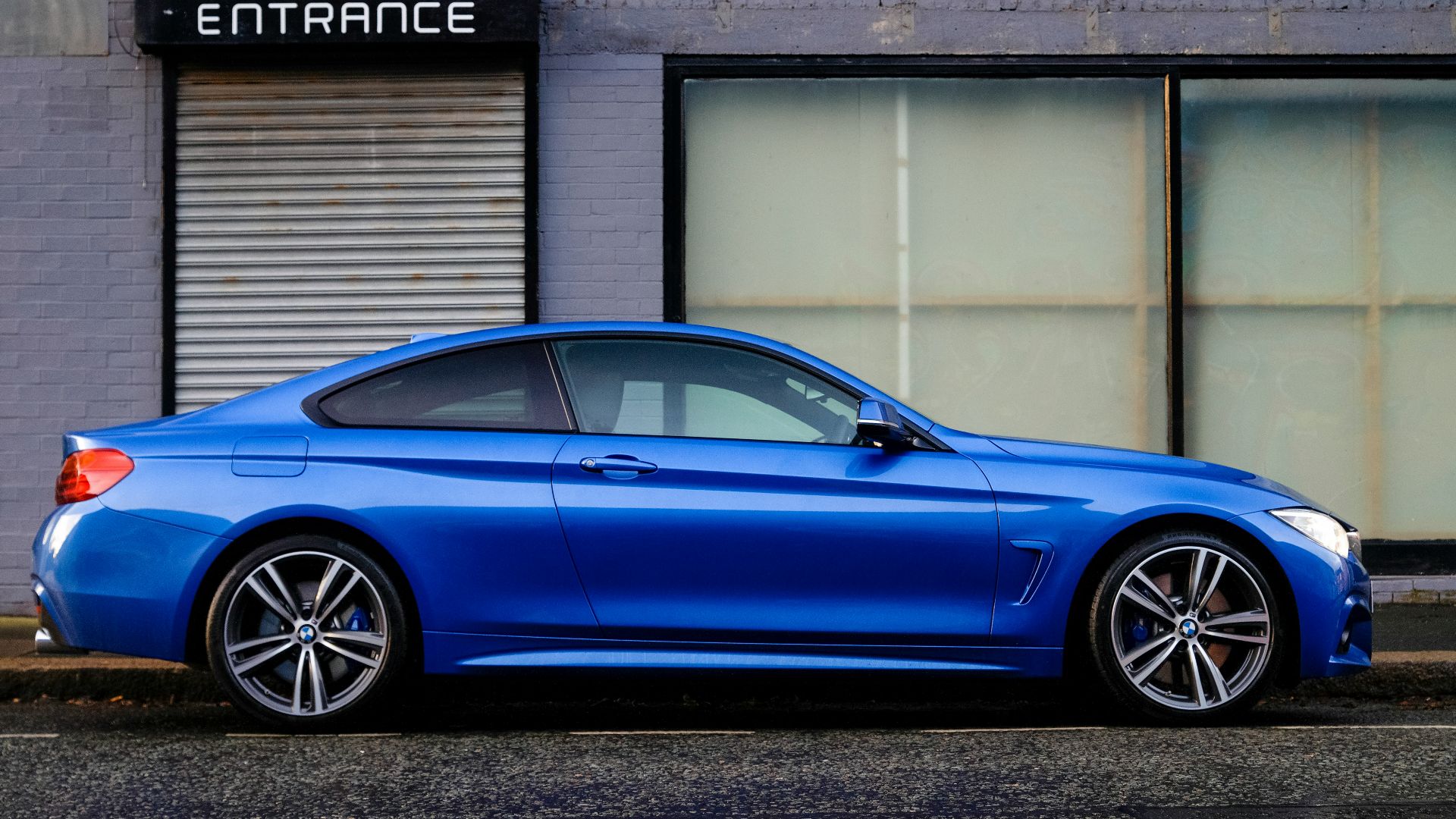 blue coupe beside gray house