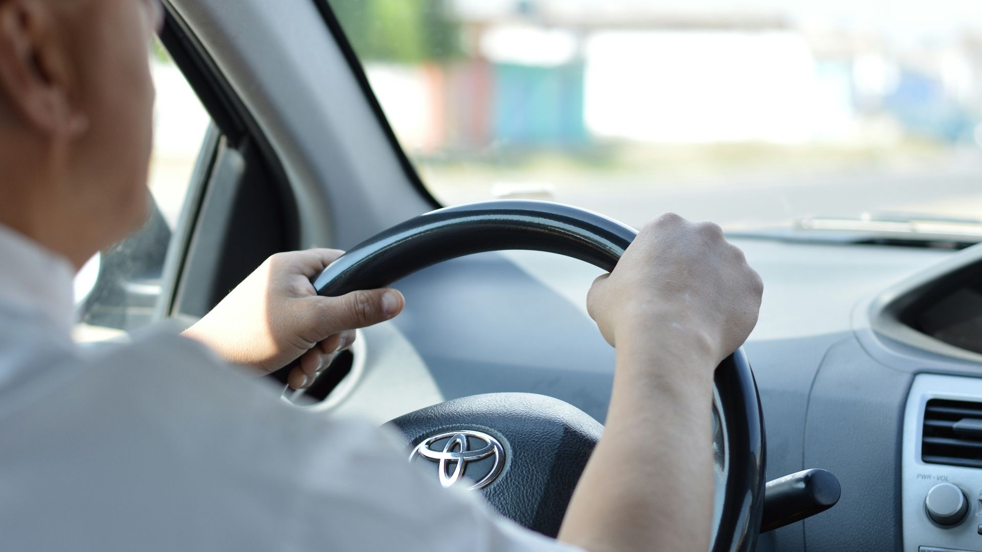 person in white long sleeve shirt driving car