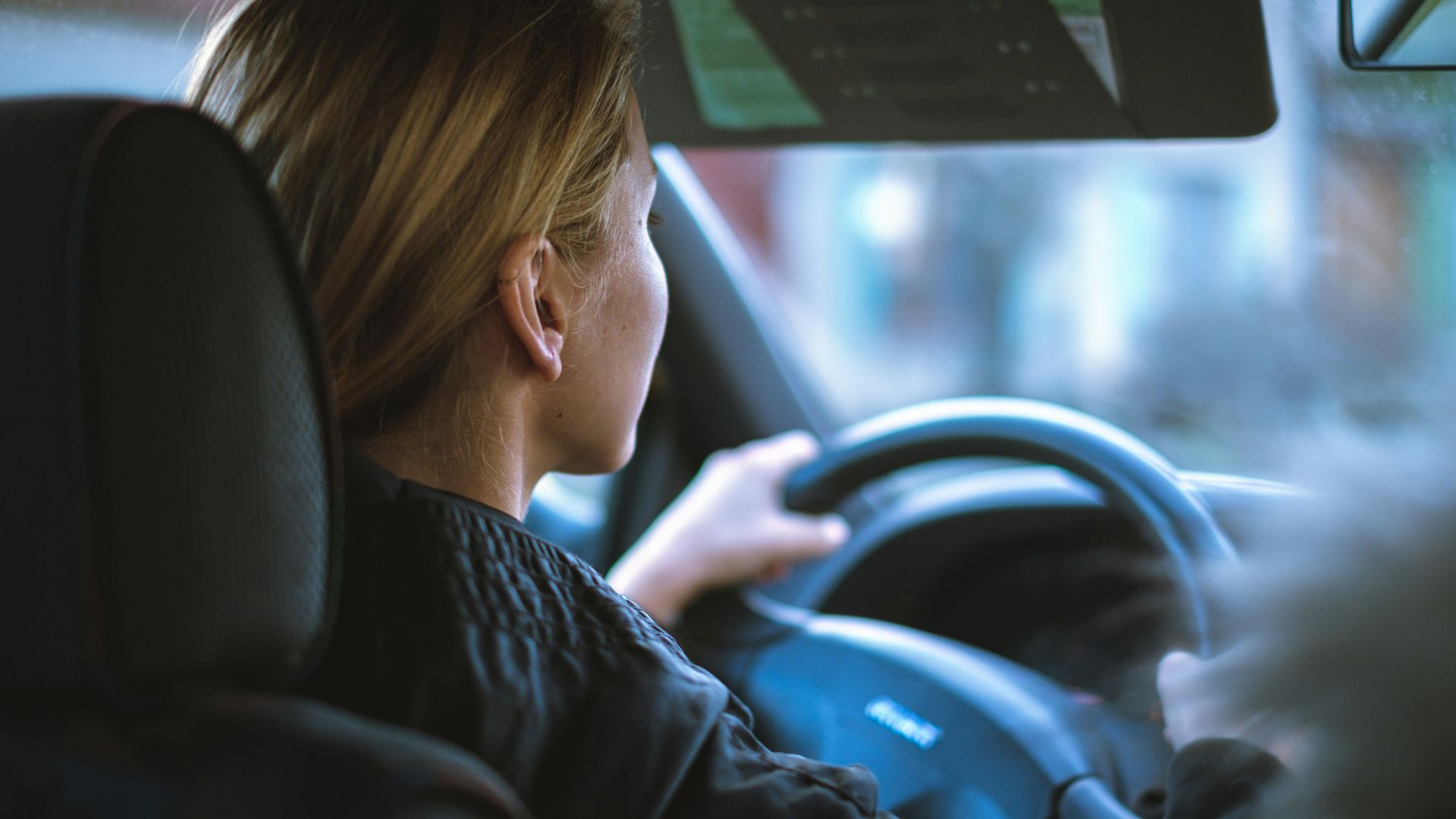 a woman sitting in a car with a steering wheel