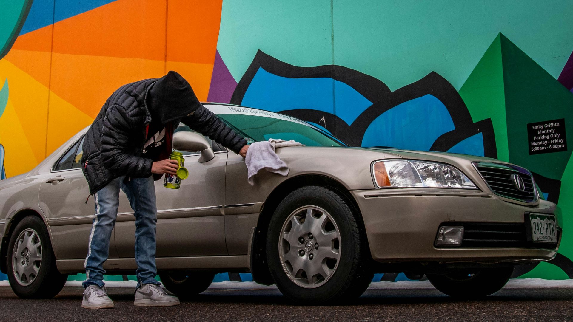 man in black jacket and blue denim jeans standing beside silver car