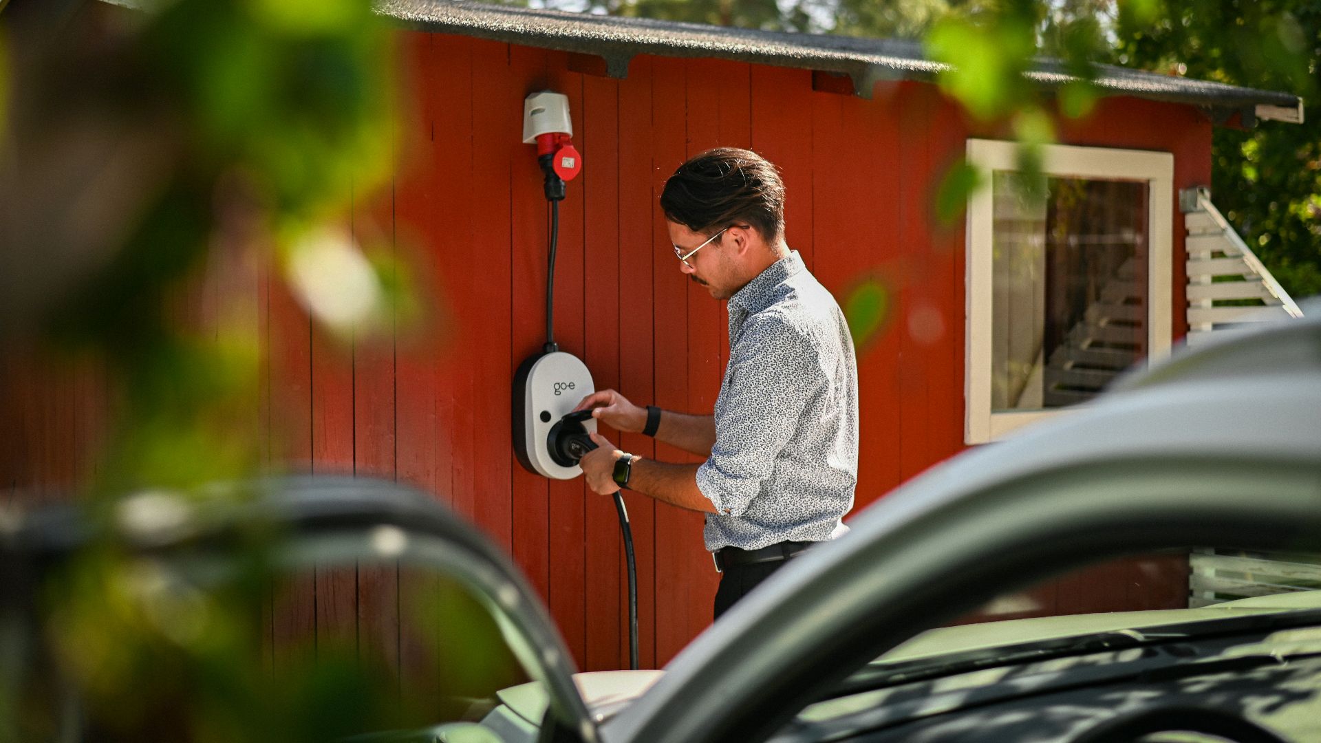 Man plugging in an electric car charger.