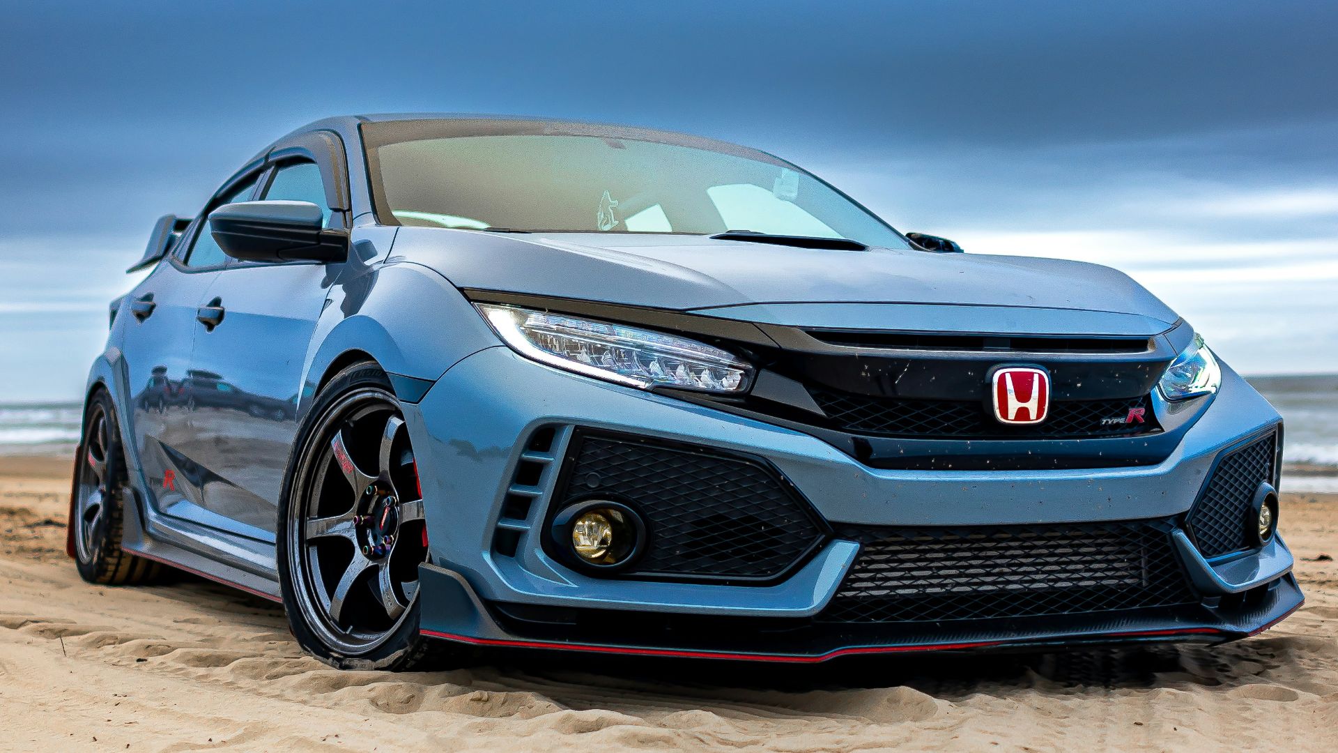 a silver car parked on top of a sandy beach