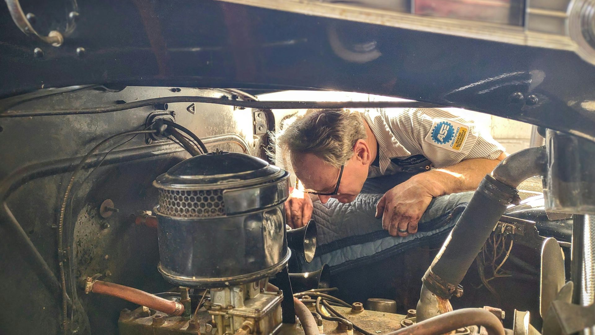 a man working on a car engine in a garage