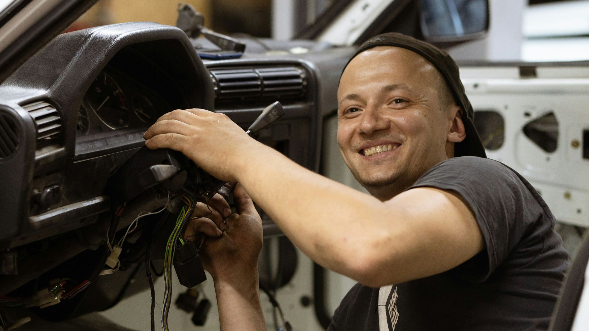 man in black crew neck t-shirt holding black car steering wheel