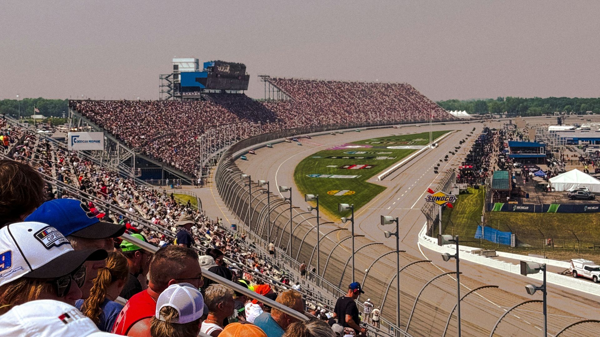 Race fans watch a car race from the stands.