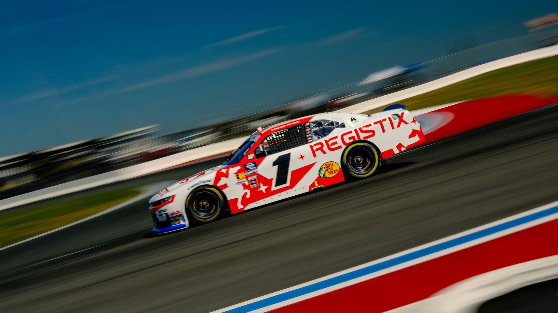 Race car speeds around a track with motion blur.