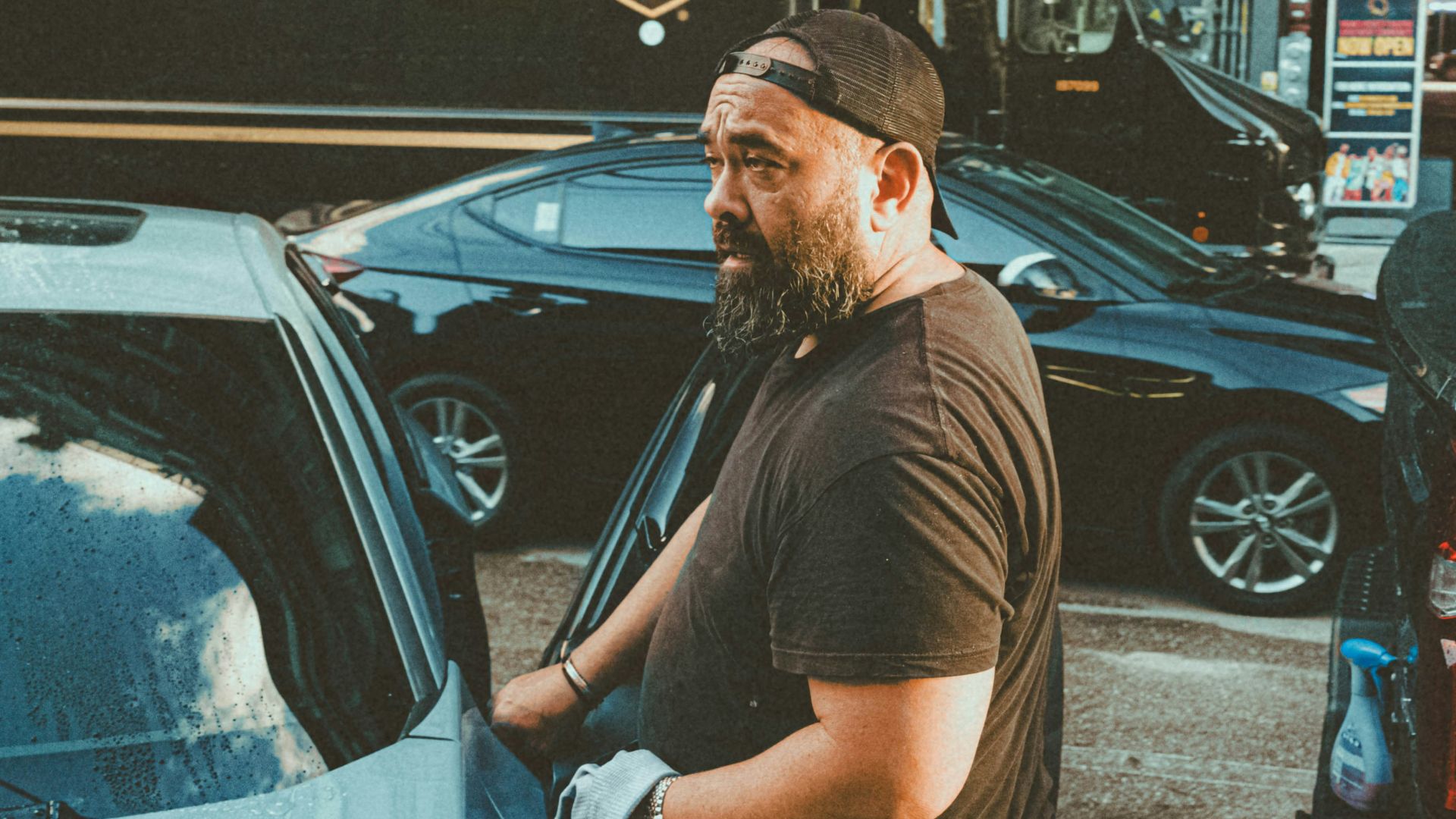 a man standing next to a parked car in a parking lot
