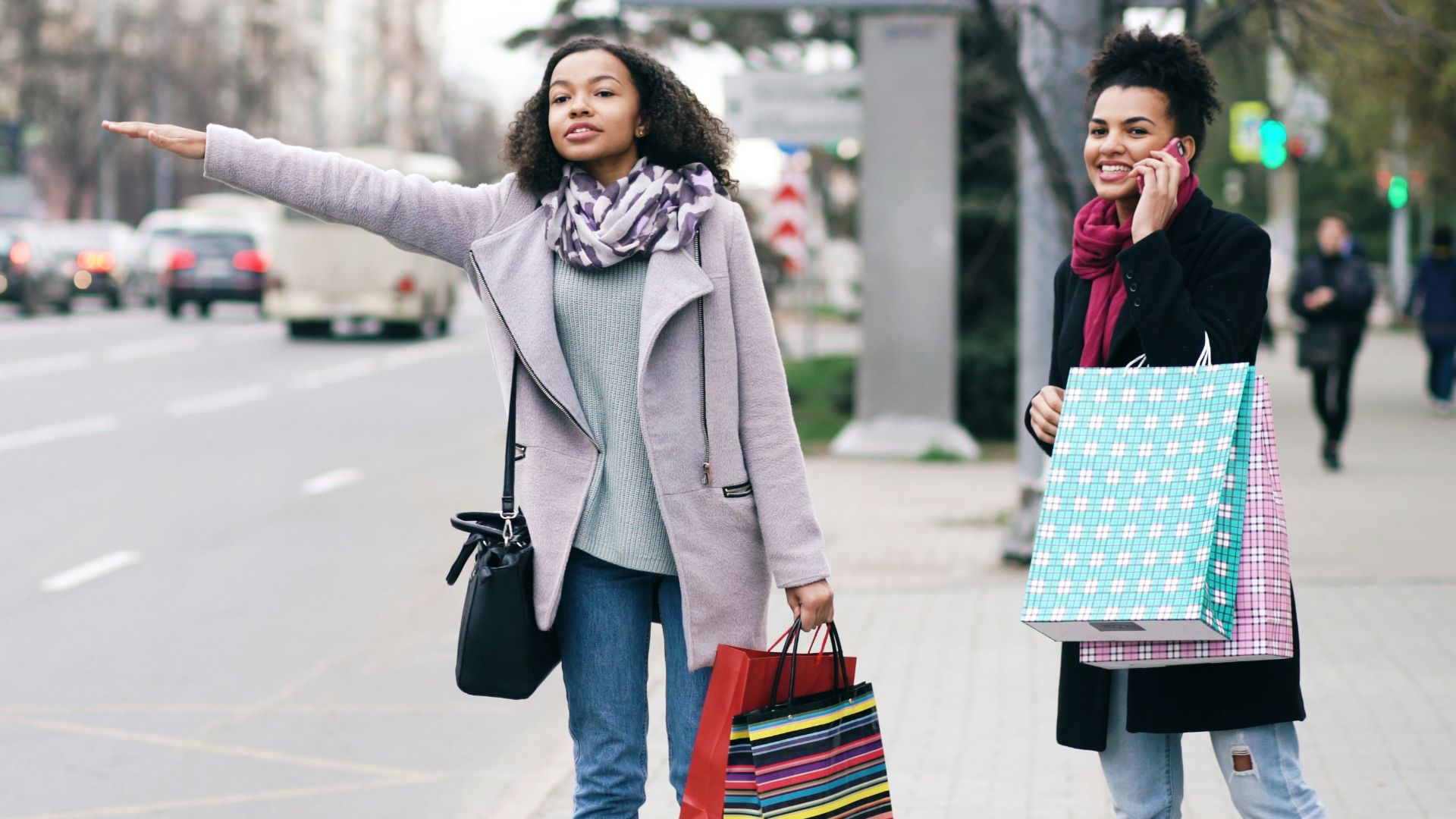 Two women hailing a taxi on city street