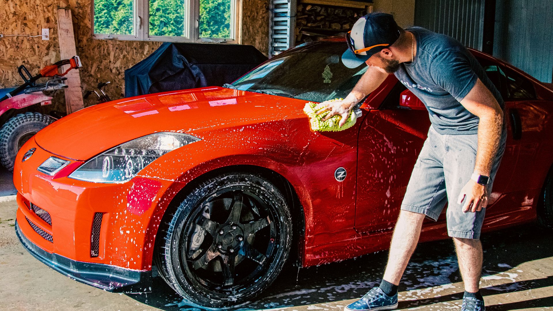a man washing a red sports car in a garage