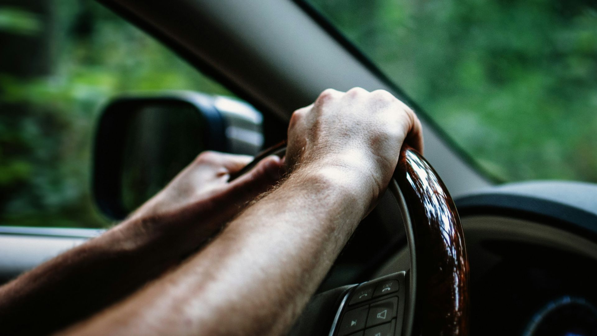 person holding car steering wheel