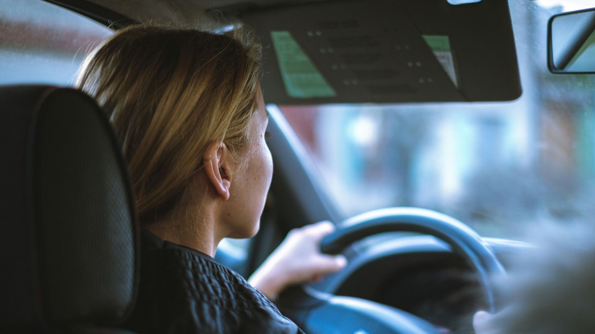 a woman sitting in a car with a steering wheel