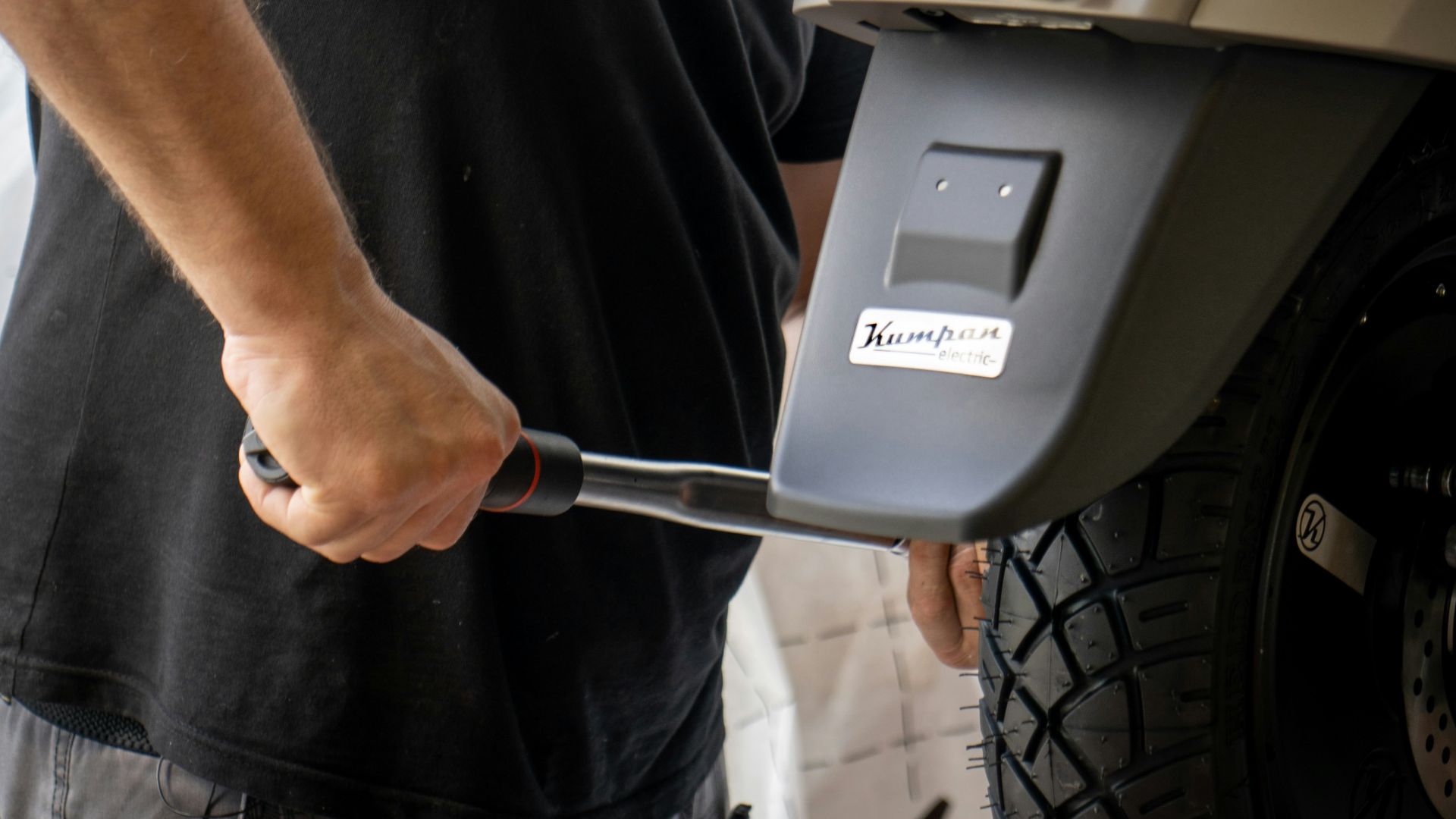 man in black crew neck t-shirt holding black and silver hand tool