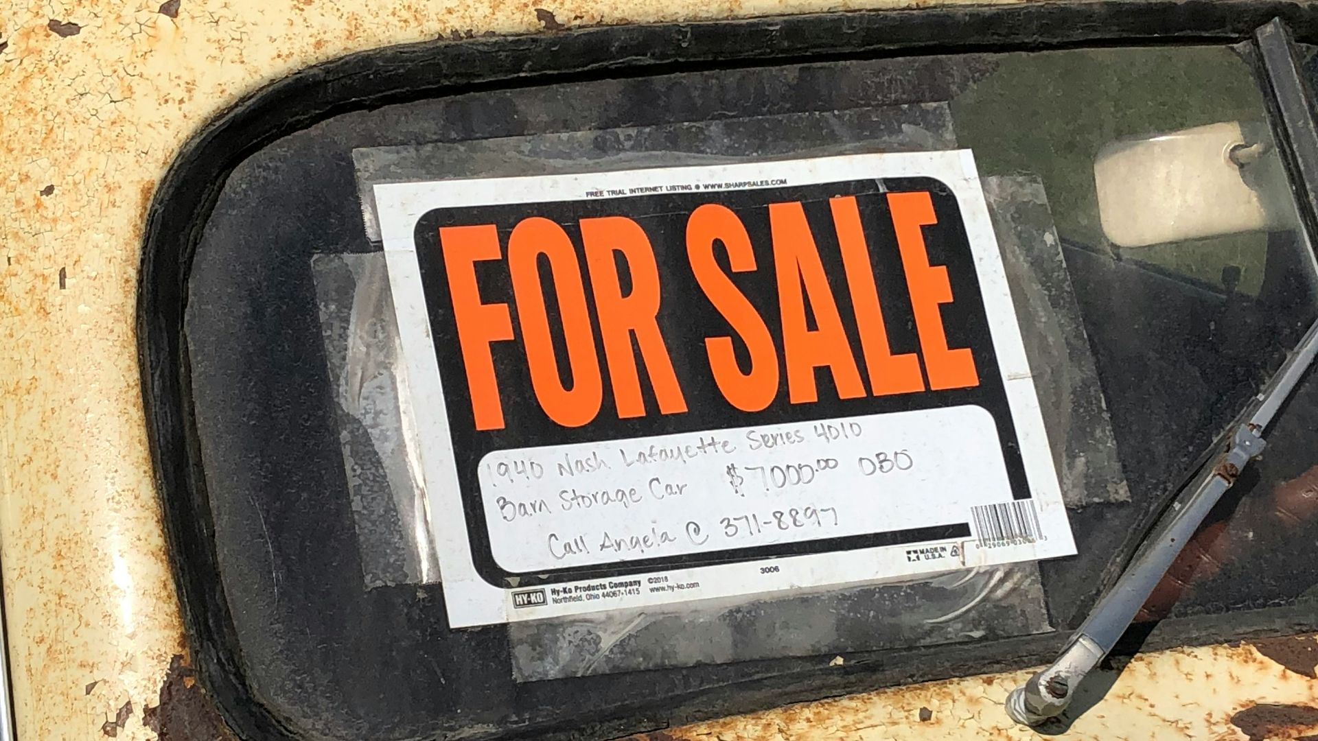 a rusted out car with a for sale sign on it