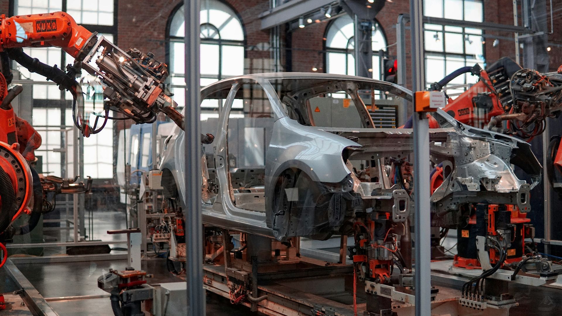 gray vehicle being fixed inside factory using robot machines