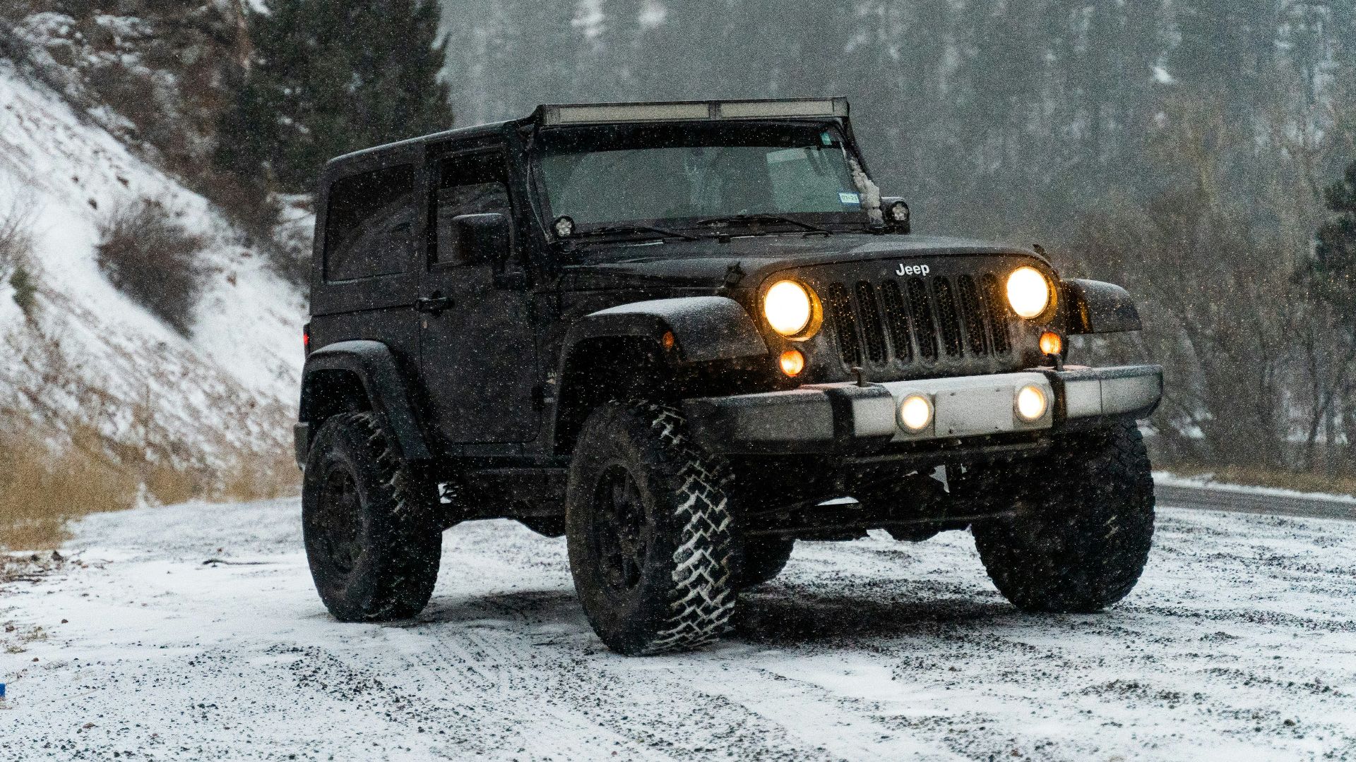 a black jeep driving down a snow covered road