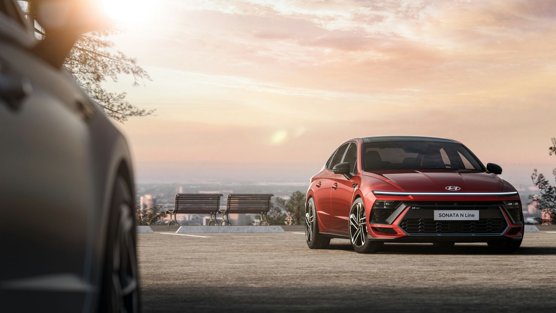 a red car parked next to a park bench