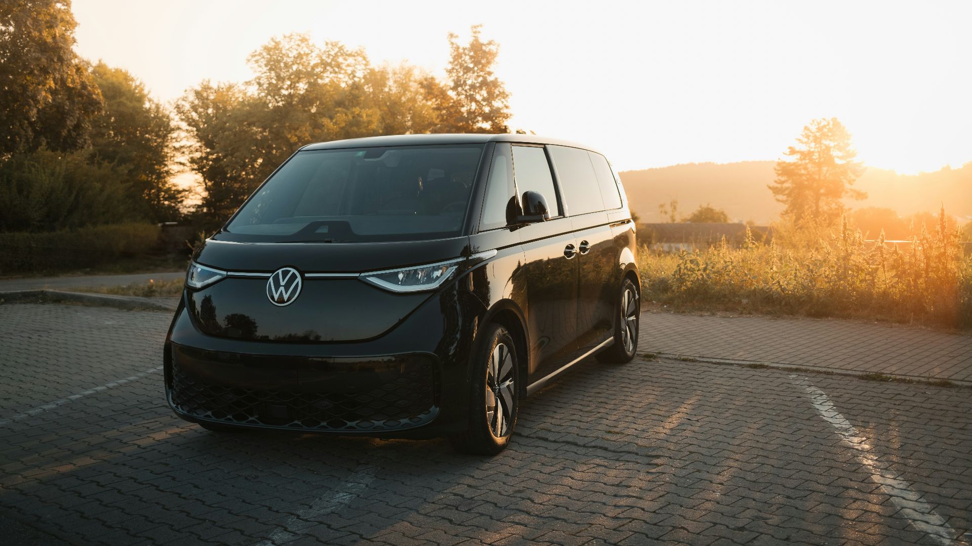 A black van driving down a road next to a forest