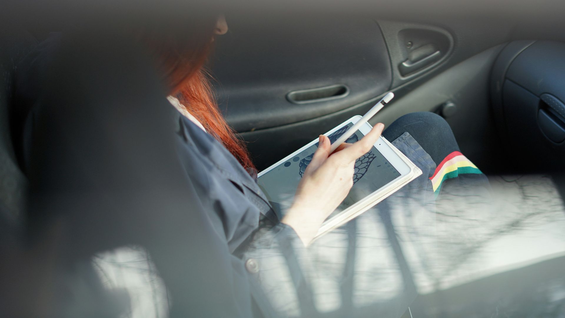 woman holding a Apple Pencil inside black car