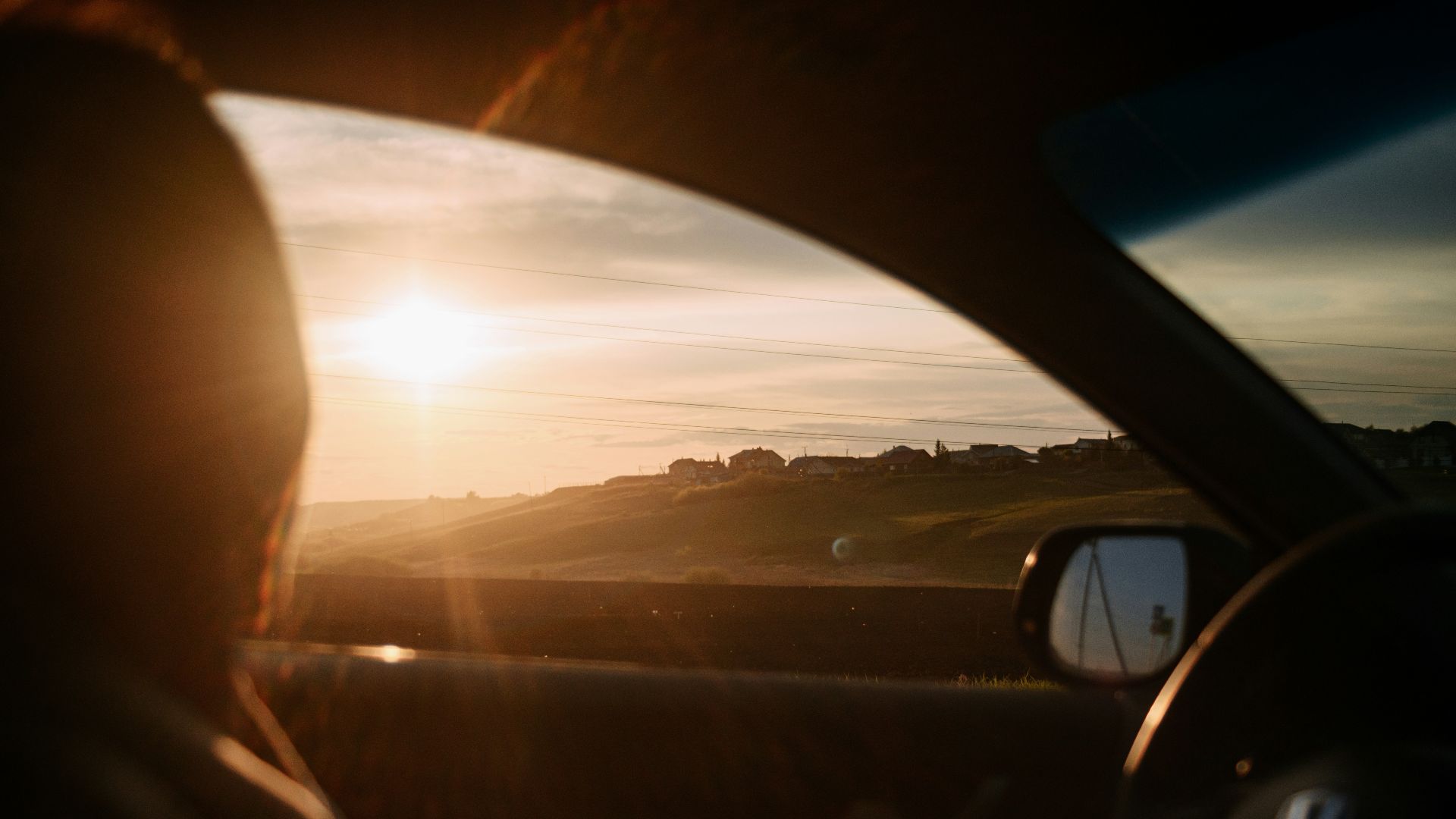 the sun is setting in the distance behind a car