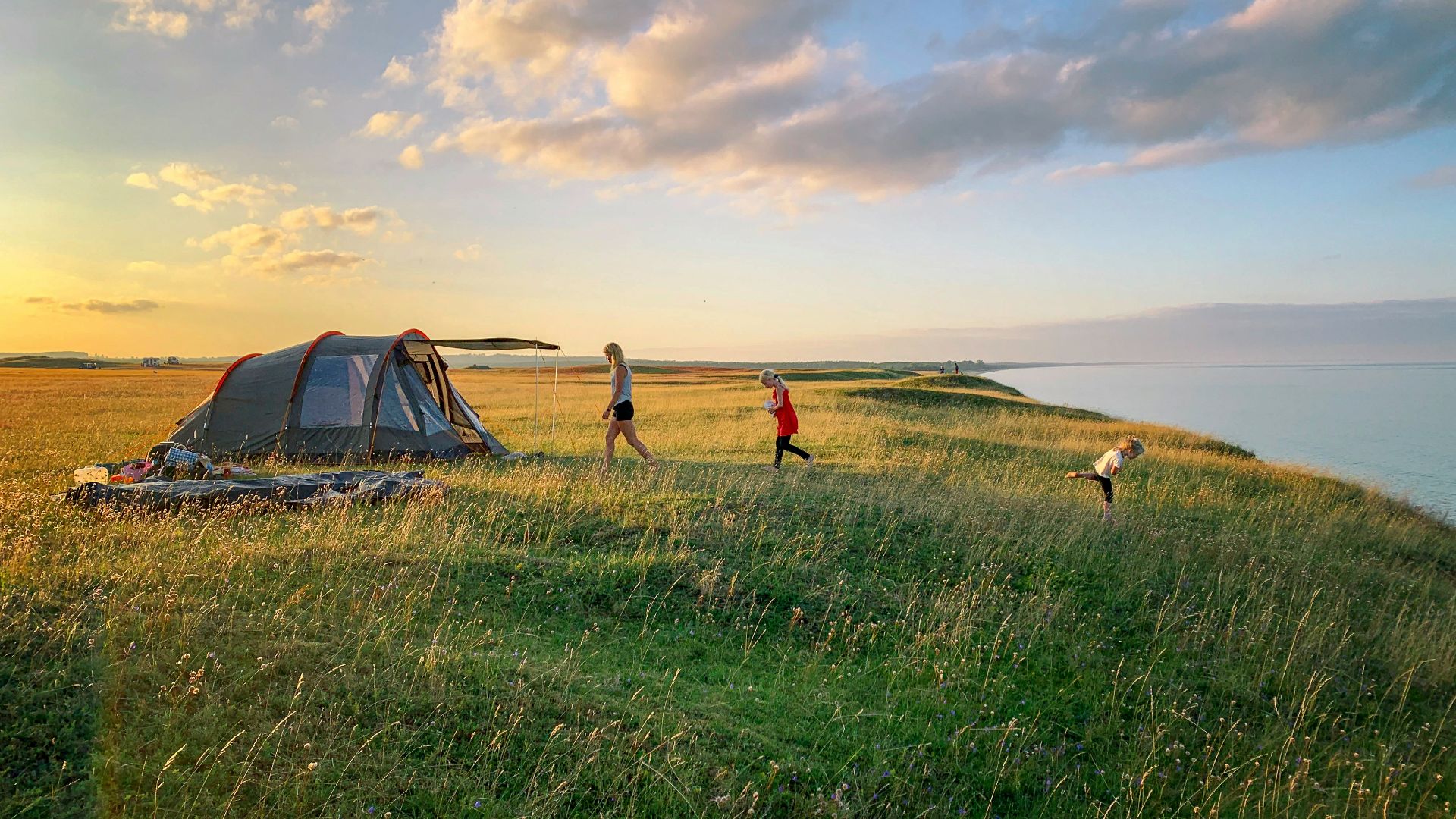 toddler walking on green grass with set-up tent during golden hour