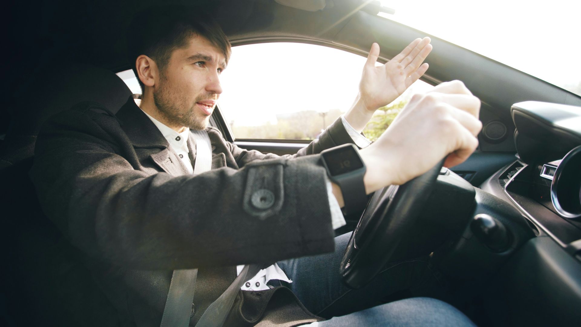 Man driving a car, gesturing with hand.