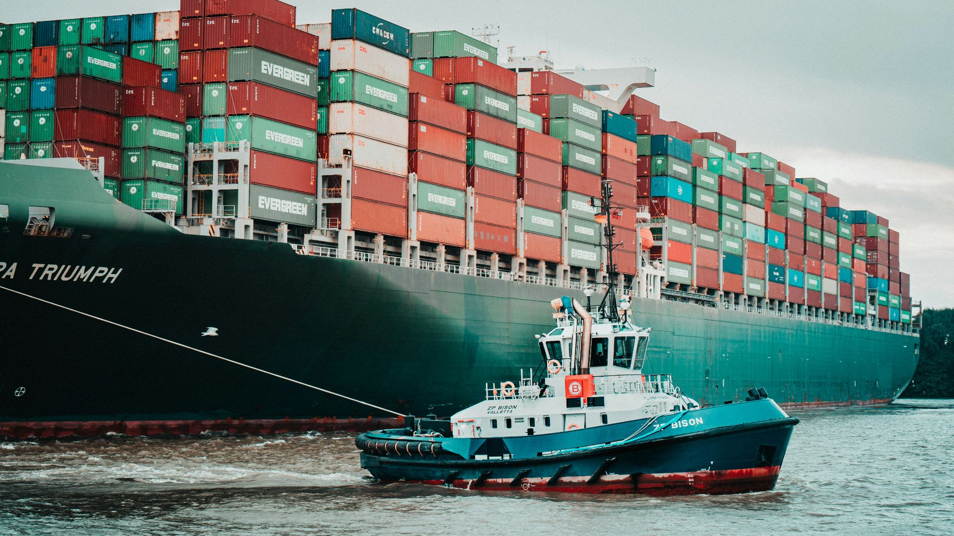 a tug boat pulling a large container ship
