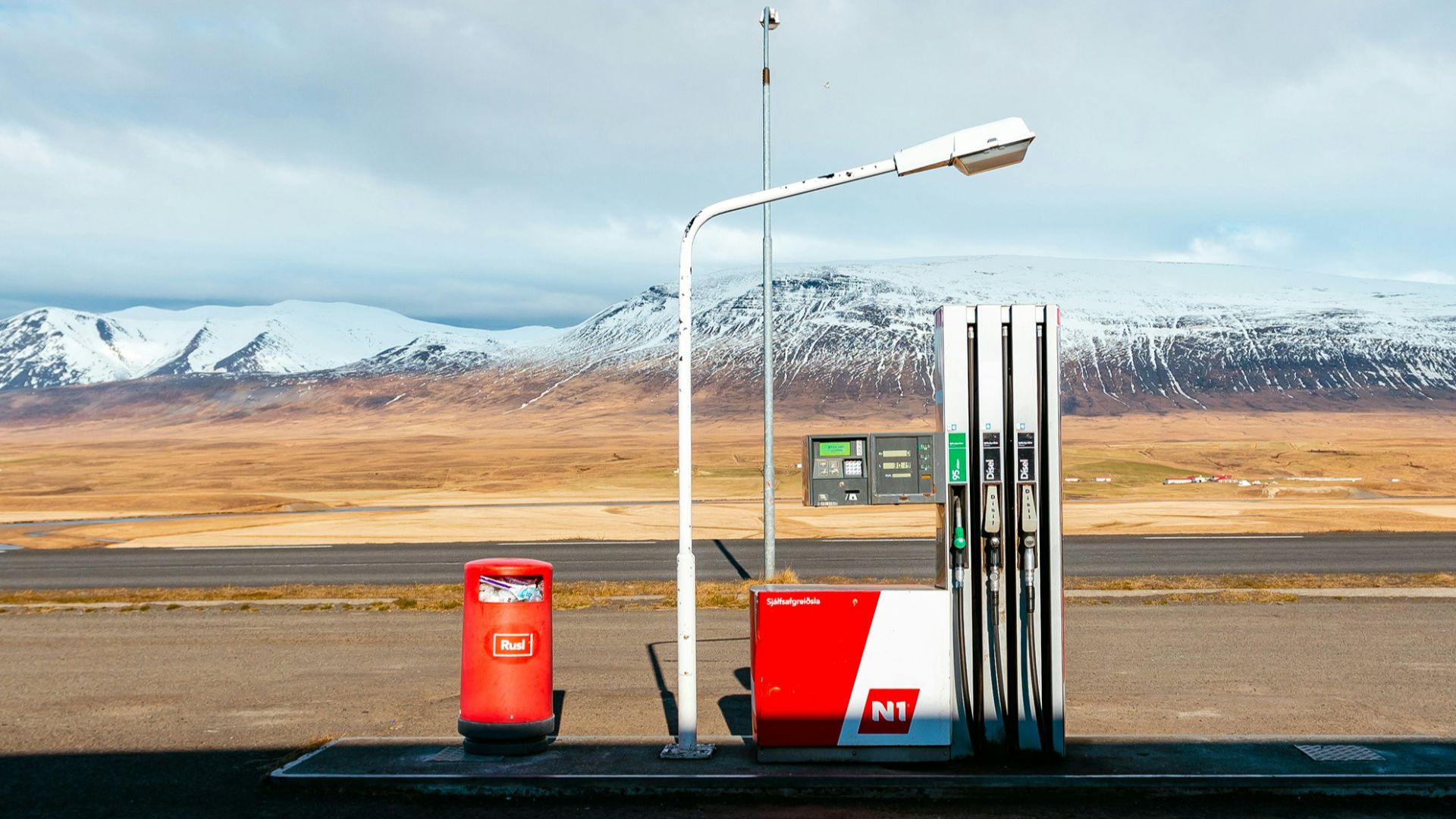 empty gas station near empty road facing snow capped mountain at daytime