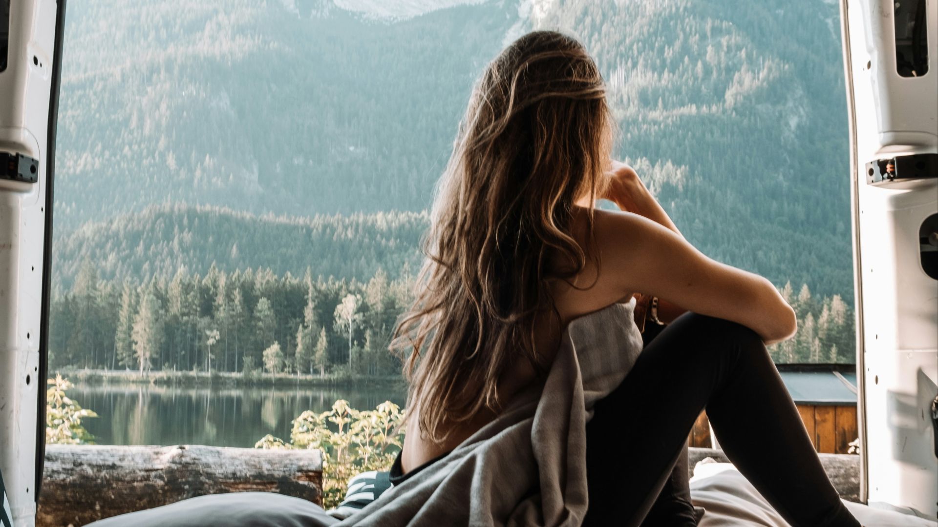 woman in black tank top and black pants sitting on bed