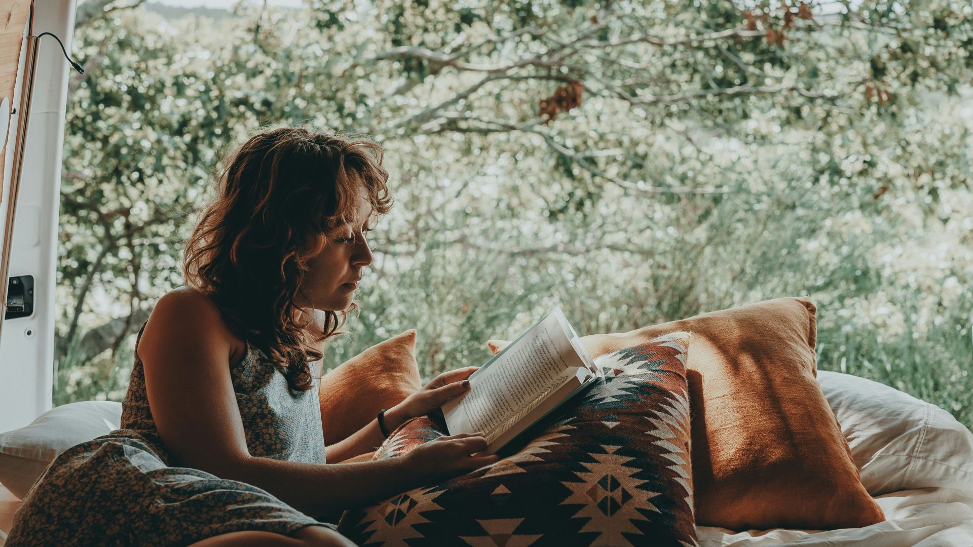 a woman sitting on a bed reading a book